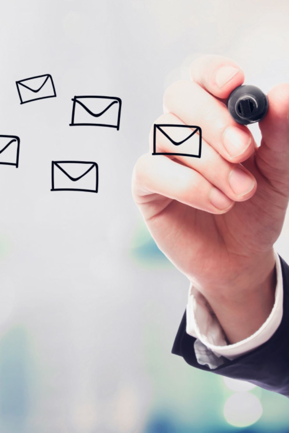 Eine Hand malt mit einem Edding E-Mail-Icons in die Luft