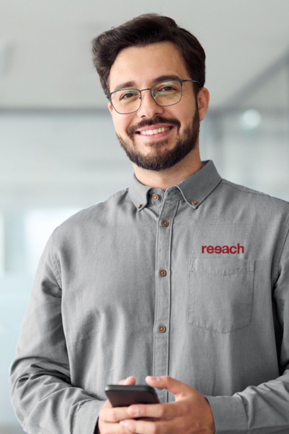 Ein Mann mit Brille und grauem Shirt hält ein Handy