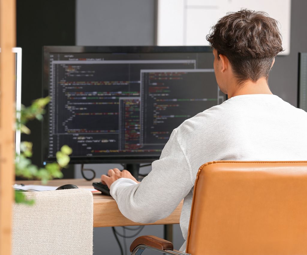 Webdesigner vor dem Computer mit geöffnetem Code